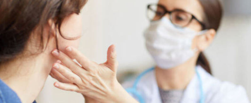 doctora palpando garganta de paciente