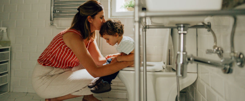 Mamá ayudando a su hijo ir al baño