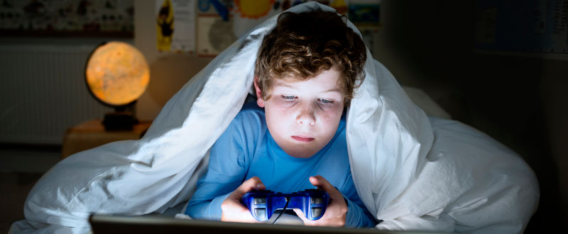 Niño jugando videojuegos en la noche