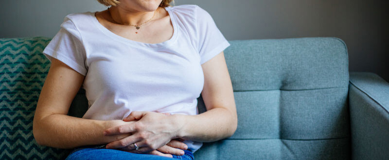 Mujer sentada en un sillón con la manos en el estómago