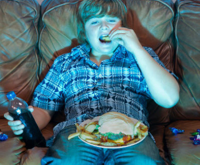 adolescente ve televisión mientras come comida chatarra