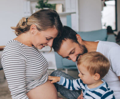 mamá embarazada, papá e hijo tocan la zona donde esta el bebe en gestación