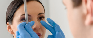 Doctor revisa nariz de paciente mujer - Rinoplastia