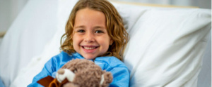 niña rubia feliz en cama de hospital