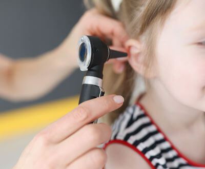 otorrino examinando oído de niña paciente