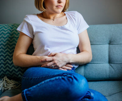 Mujer sentada en un sillón con la manos en el estómago